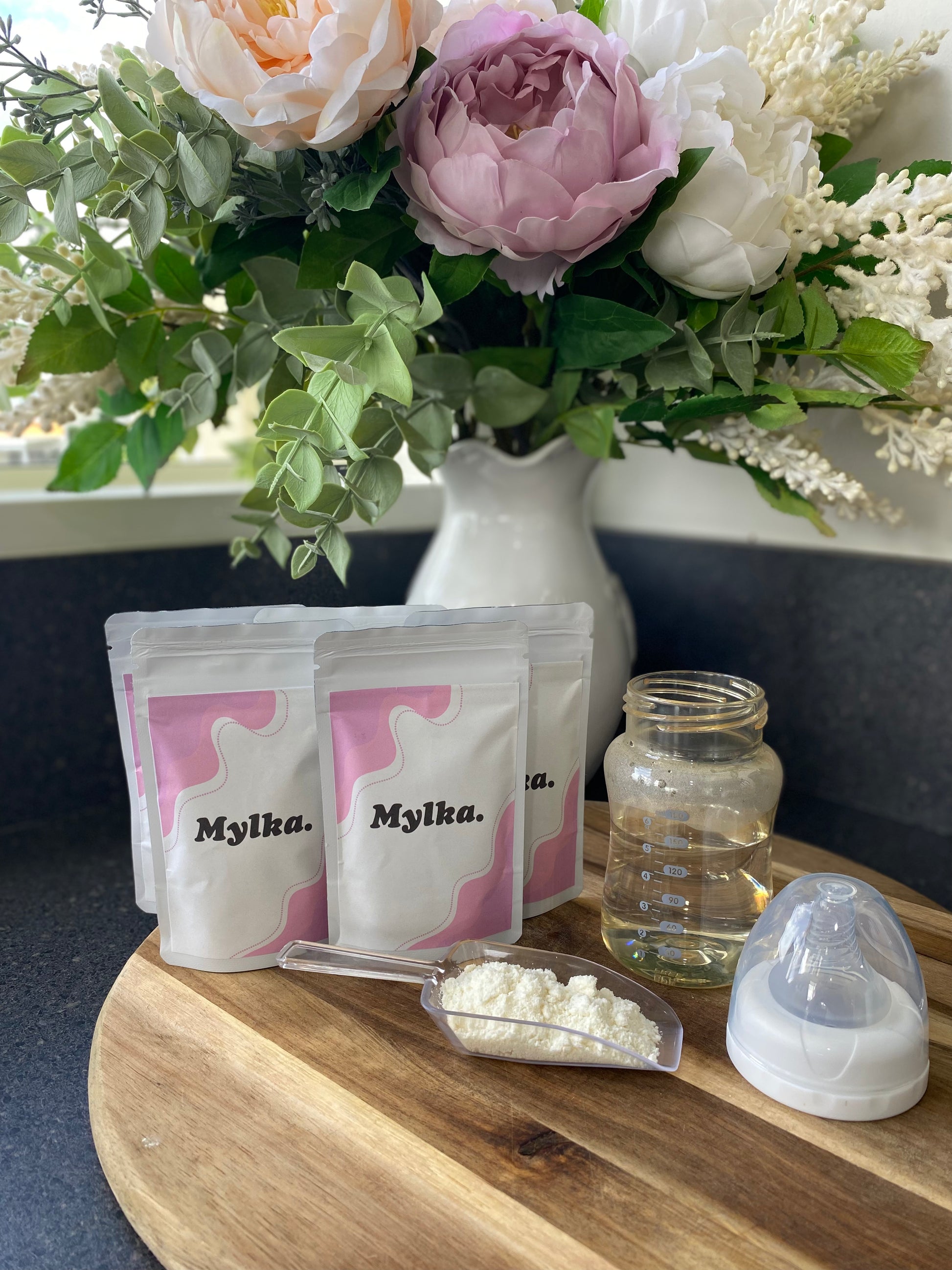 Mylka single serve pouches with a scoop of powder and a baby bottle ready to be made up. 